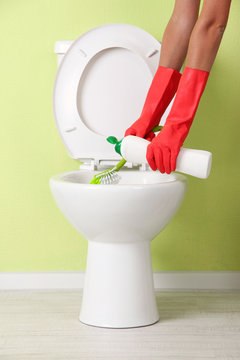 Woman hand with spray bottle cleaning a toilet bowl in a