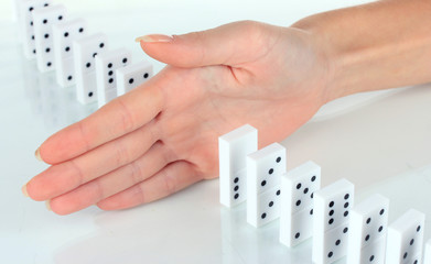 Hand stopping dominoes falling isolated on white