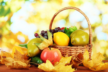 Naklejka na ściany i meble Different fruits and vegetables with yellow leaves in basket