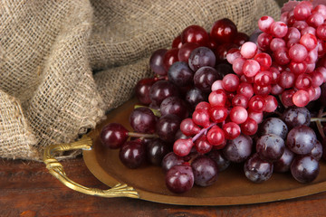 Golden tray with grape on wooden background