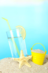 Beach cocktail in sand on blue background