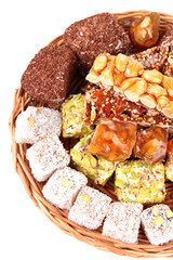 Tasty oriental sweets on wicker tray, isolated on white