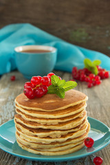 Homemade pancakes with honey and berries on a wooden table.