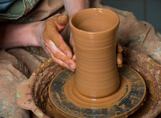 hands of a potter, creating an earthen jar on the circle