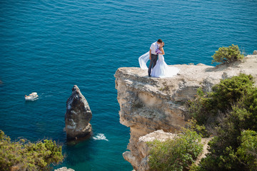 Fototapeta na wymiar wedding couple stands on a cliff above blue sea