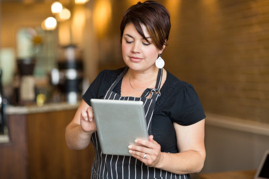 Female Owner Using Digital Tablet In Cafe