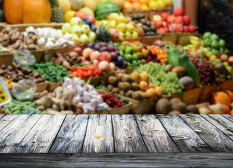 Background with empty wooden table and blured fruits and vegetab