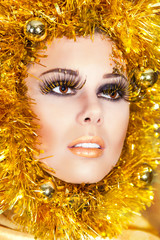 Christmas makeup of beautiful woman with gold tinsel on face