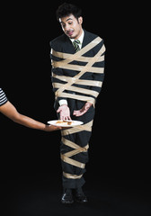 Businessman tied up with adhesive tape and looking to toast with greed