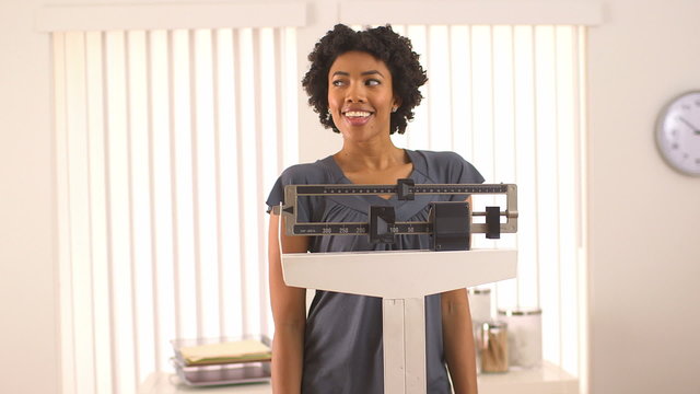 African American woman dancing on scale happy about weight loss