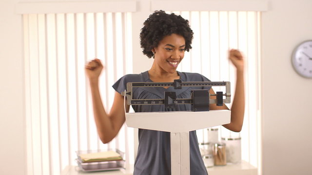 Black woman excited about weight loss on scale
