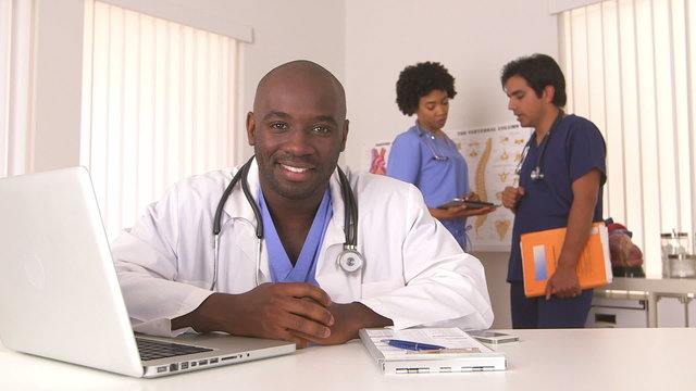 African American doctor smiling with colleagues in background