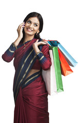 Traditionally Indian woman talking on a cell phone with shopping bags