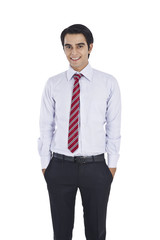 Businessman standing with his hands in pockets and smiling