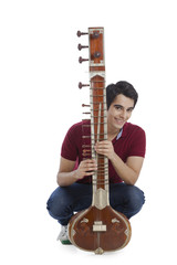 Portrait of a man playing a sitar and smiling