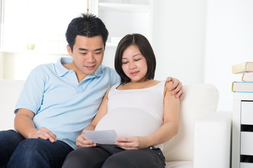 chinese pregnant mother and her husband looking at ultrascan pho