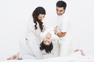 Happy parents playing with their son on the bed