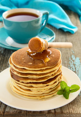 Homemade pancakes with honey and berries on a wooden table.