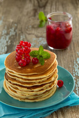 Homemade pancakes with honey and berries on a wooden table.