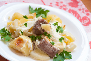 Baked potatoes with meat in a creamy sauce