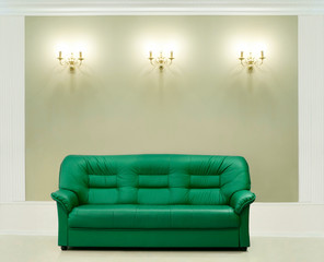 The green leather sofa, is put about a wall with candelabrums