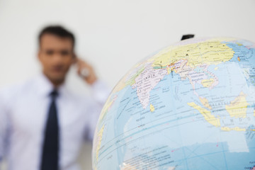 Close-up of a globe with a businessman in the background