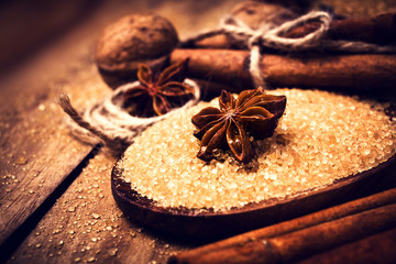Cinnamon sticks, nuts and star anise on brown sugar, macro. Baki