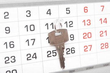 A house key on a calendar background, paying your mortgage on ti