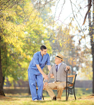 Healthcare professional talking senior man seated on bench