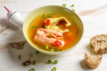 Salmon soup served with bread on old wooden table