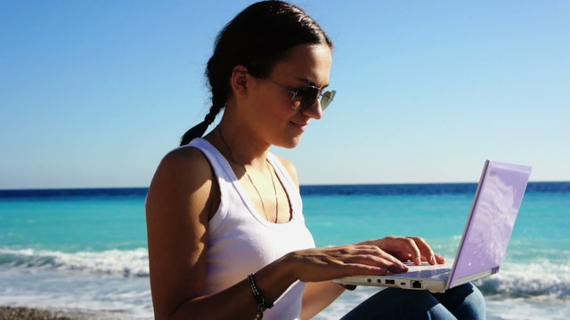 Young woman with laptop on the summer beach