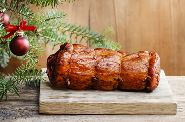 Christmas smoked ham under fir branch. Wooden background