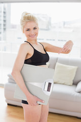 Fototapeta na wymiar Woman in sportswear carrying scale in fitness studio