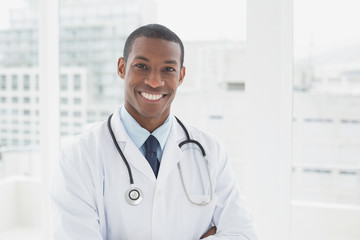 Confident smiling male doctor in a medical office - obrazy, fototapety, plakaty