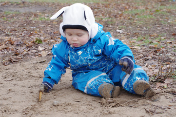 baby paints with stick sitting on ground