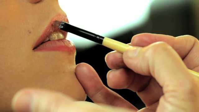 Maquilladora pintando labios de modelo