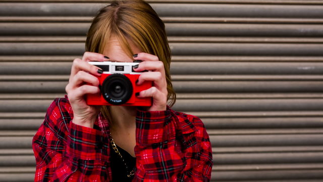 Teenage hipster woman having fun taking pictures with old camera