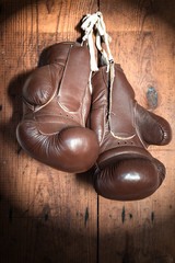 old Boxing Gloves, on wooden wall in the Spotlight