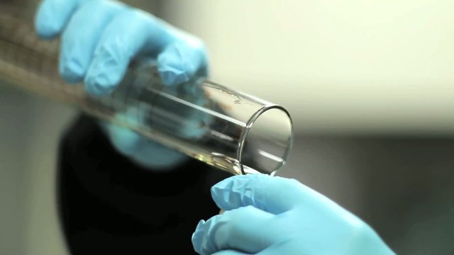 Qu&iacute;mico vertiendo l&iacute;quido en tubo de ensayo