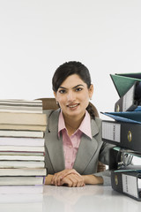 Stack of books and binders in front of a businesswoman at desk