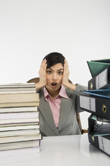 Stack of books and binders in front of a businesswoman at desk