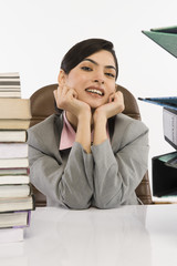 Stack of books and binders in front of a businesswoman at desk
