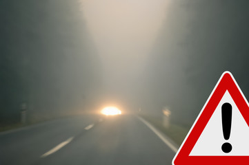 Bad weather driving - foggy road with traffic sign