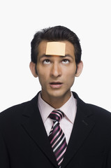 Businessman looking at a sticky note on his forehead