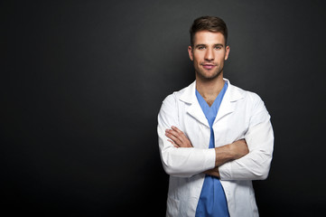 Portrait of confident young medical doctor on dark background