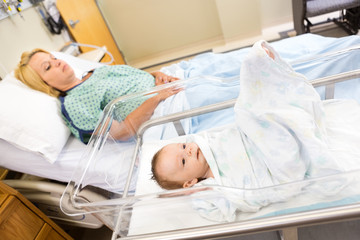 Babygirl Lying In Bassinet With Woman On Hospital Bed