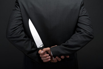 Businessman with knife behind his back