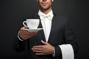 Waiter in suit holding coffee cup