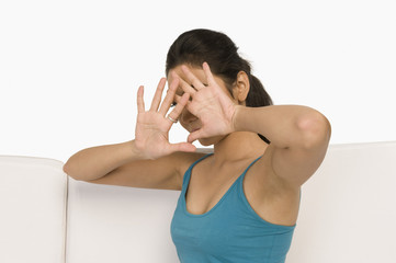 Woman sitting on a couch and covering her face with her hands