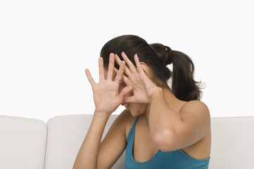 Woman sitting on a couch and covering her face with her hands